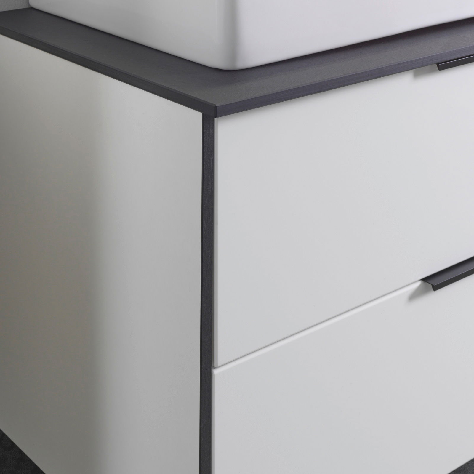 Nahaufnahme eines modernen Waschtisch-Sets mit weißem Schrank und dunkler Arbeitsplatte, seitliche Perspektive