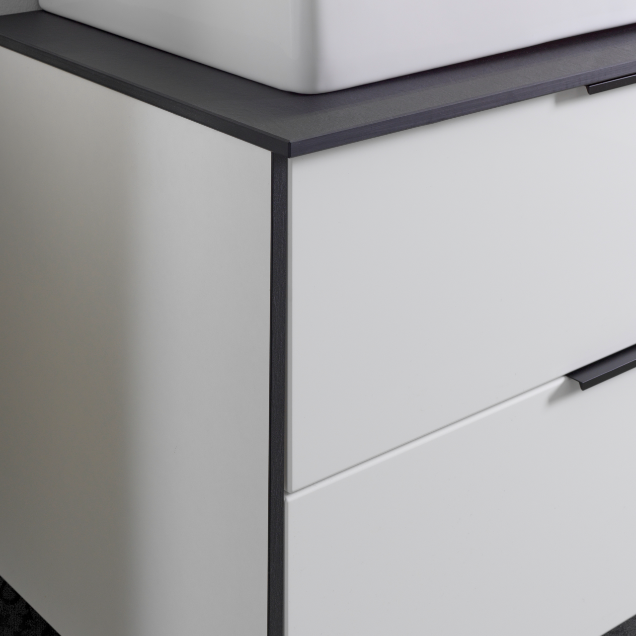 Nahaufnahme eines modernen Waschtisch-Sets mit weißem Schrank und dunkler Arbeitsplatte, seitliche Perspektive