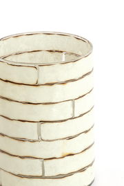 Nahaufnahme eines dekorativen Teelichthalters mit einem gestreiften, cremefarbenen Design und metallischen Akzenten, seitliche Perspektive.