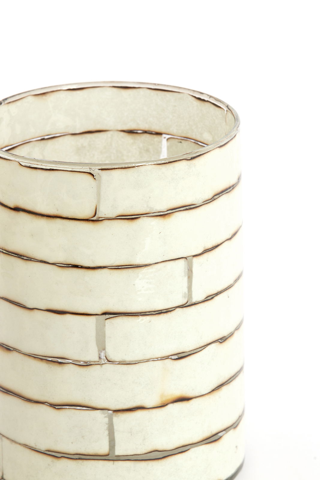 Nahaufnahme eines dekorativen Teelichthalters mit einem gestreiften, cremefarbenen Design und metallischen Akzenten, seitliche Perspektive.