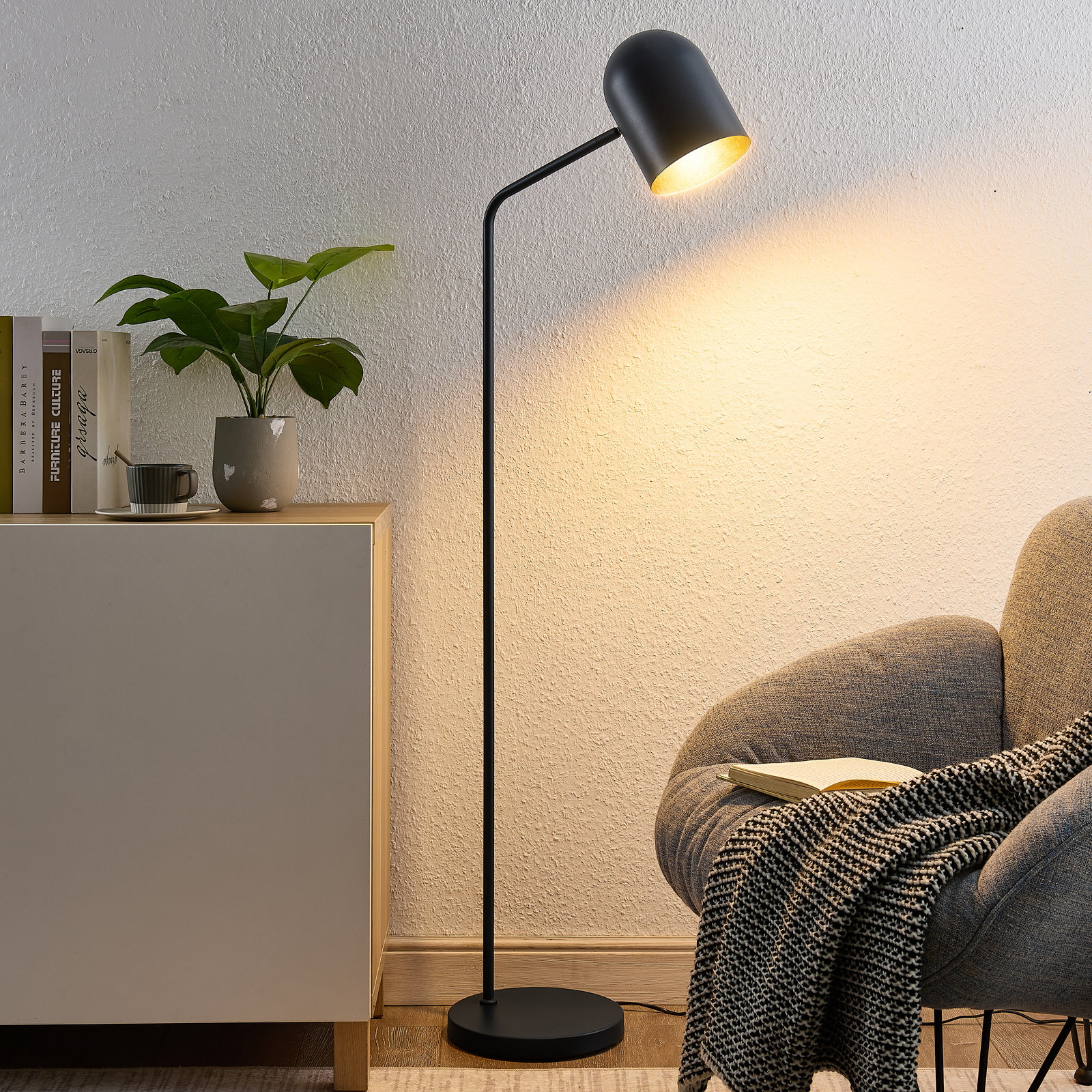 Moderne schwarze Stehleuchte in einem gemütlichen Wohnzimmer, seitliche Perspektive.