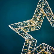 Nahaufnahme eines LED-Sterns mit 960 LEDs, die in einem filigranen Muster auf einem weißen Rahmen angeordnet sind, vor einem blauen Hintergrund.