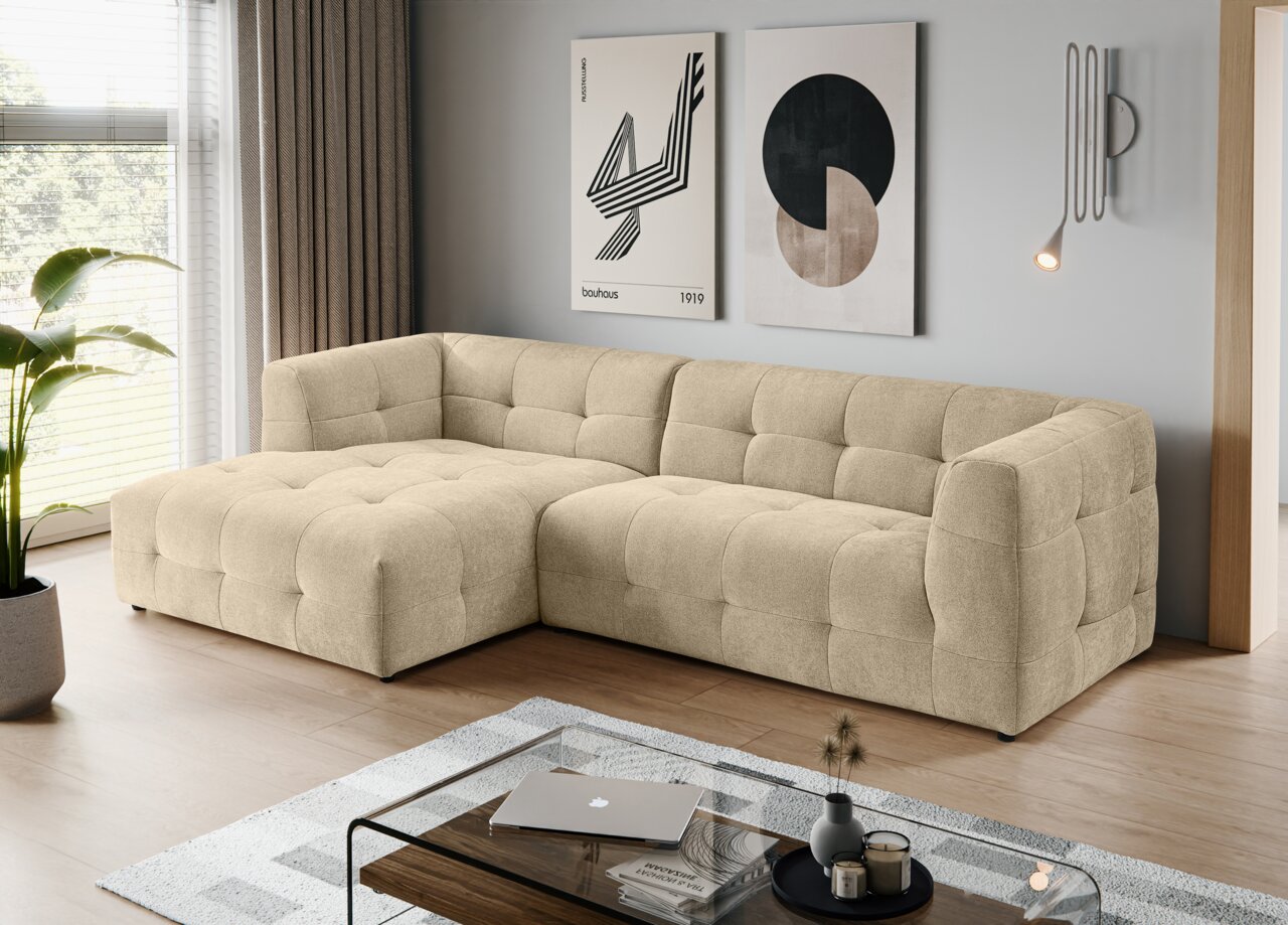 MID.YOU Ecksofa TENSO Beiges, gepolstertes L-förmiges Ecksofa mit Steppung und breiter Ottomane in modernem Wohnzimmer, fotografiert aus schräger Frontperspektive.