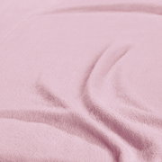 Nahaufnahme eines rosa Spannbetttuchs mit weicher Textur und Falten.