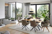 Moderner Essbereich mit großem Holztisch und bequemen Armlehnstühlen, umgeben von großen Fenstern mit Blick ins Grüne. Perspektive: seitlich.