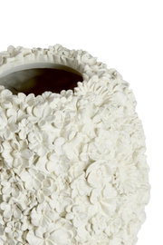 Close-up van een witte vaas met gedetailleerd bloemenreliëf, gezien van bovenaf.