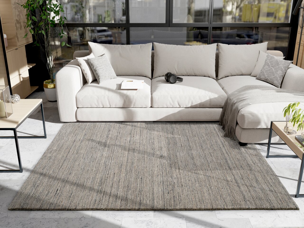 Grauer Wollteppich in einem modernen Wohnzimmer, fotografiert aus der Vogelperspektive, mit einem beigen Sofa und einem Couchtisch im Hintergrund.