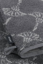 Grauer Waschhandschuh mit floralem Muster und Markenetikett, Nahaufnahme