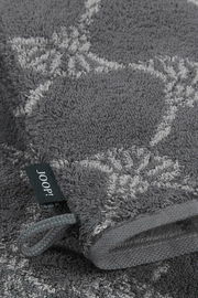 Grauer Waschhandschuh mit floralem Muster und Markenetikett, Nahaufnahme