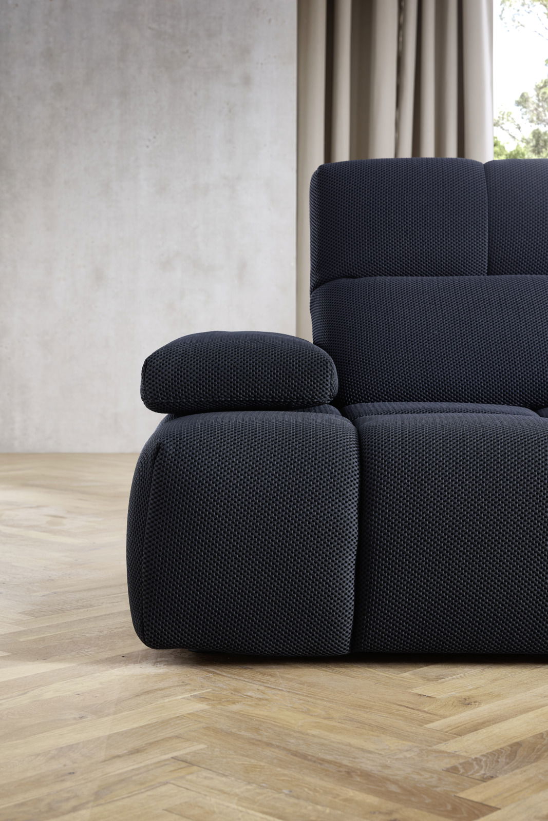 Nahaufnahme einer modernen, dunkelblauen Eckgarnitur mit strukturiertem Stoffbezug, seitliche Perspektive.