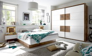 Moderne Schlafzimmermöbel mit einem weißen Schwebetürenschrank und einem Bett mit Holz- und Weißakzenten, seitliche Perspektive.