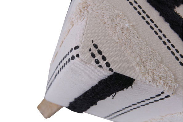 Nahaufnahme eines Hockers mit geometrischem Muster in Schwarz und Weiß, aus seitlicher Perspektive.