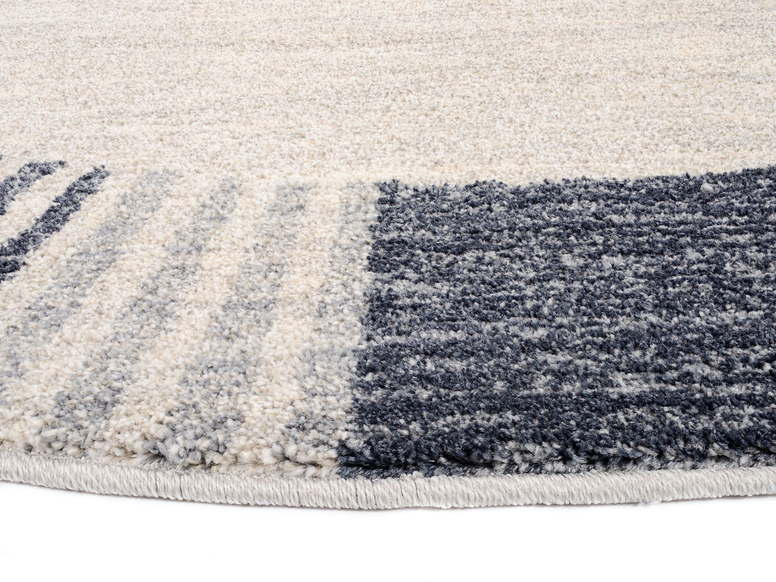 Nahaufnahme eines runden Frisé-Teppichs mit grauen und cremefarbenen Streifenmuster.