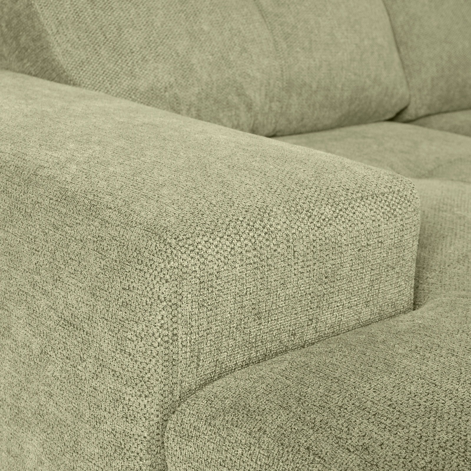 Nahaufnahme einer grünen Sofaecke mit texturierter Stoffoberfläche, Perspektive von der Seite