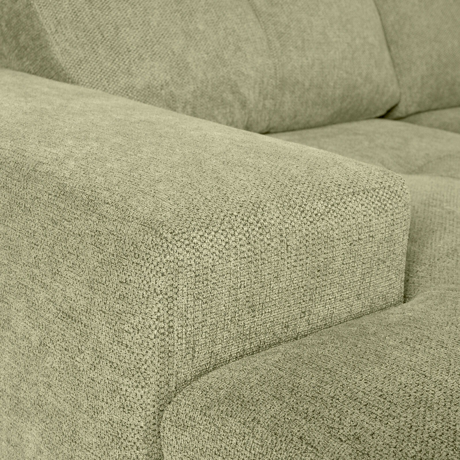 Nahaufnahme einer grünen Sofaecke mit texturierter Stoffoberfläche, Perspektive von der Seite
