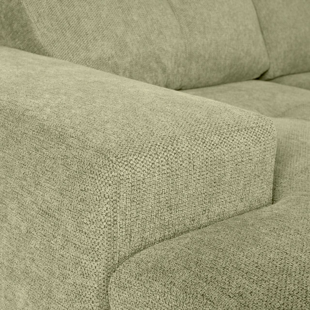 Nahaufnahme einer grünen Sofaecke mit texturierter Stoffoberfläche, Perspektive von der Seite