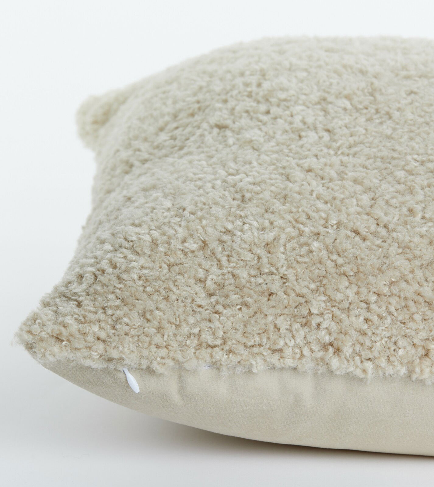 Nahaufnahme eines beigen Kissens mit flauschiger Textur, seitliche Perspektive
