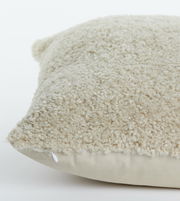 Nahaufnahme eines beigen Kissens mit flauschiger Textur, seitliche Perspektive