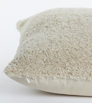 Nahaufnahme eines beigen Kissens mit flauschiger Textur, seitliche Perspektive