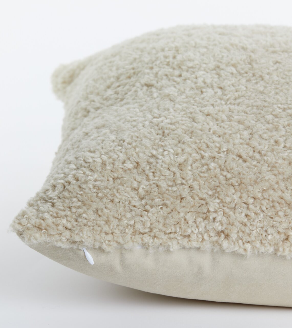 Nahaufnahme eines beigen Kissens mit flauschiger Textur, seitliche Perspektive