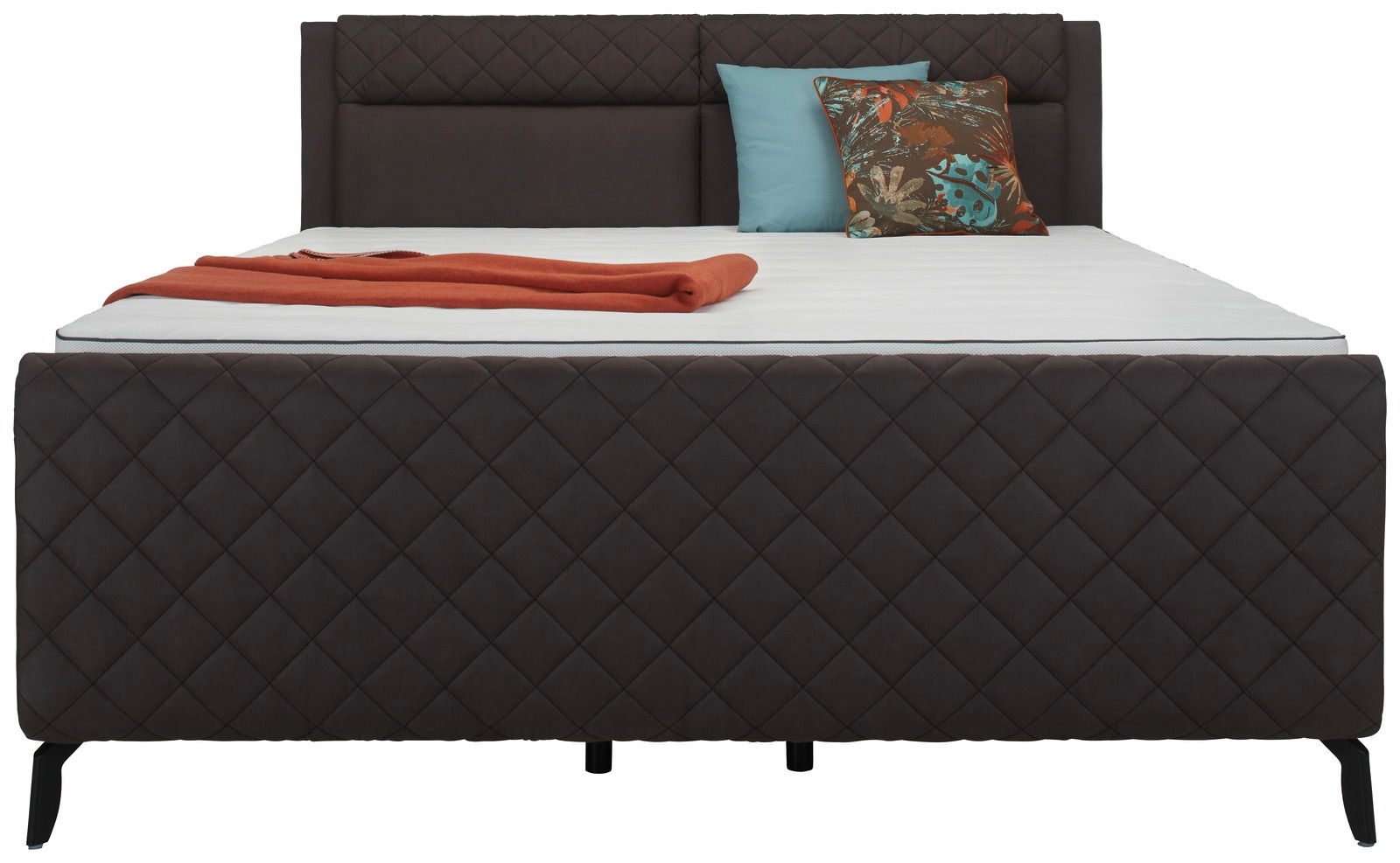 Frontale Ansicht eines eleganten Boxspringbetts mit gesteppter Oberfläche, dekoriert mit bunten Kissen und einer orangefarbenen Decke.