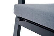 Close-up van een Comfort Plus stapelstoel met grijze bekleding en een zwart metalen frame, gezien vanaf de zijkant.