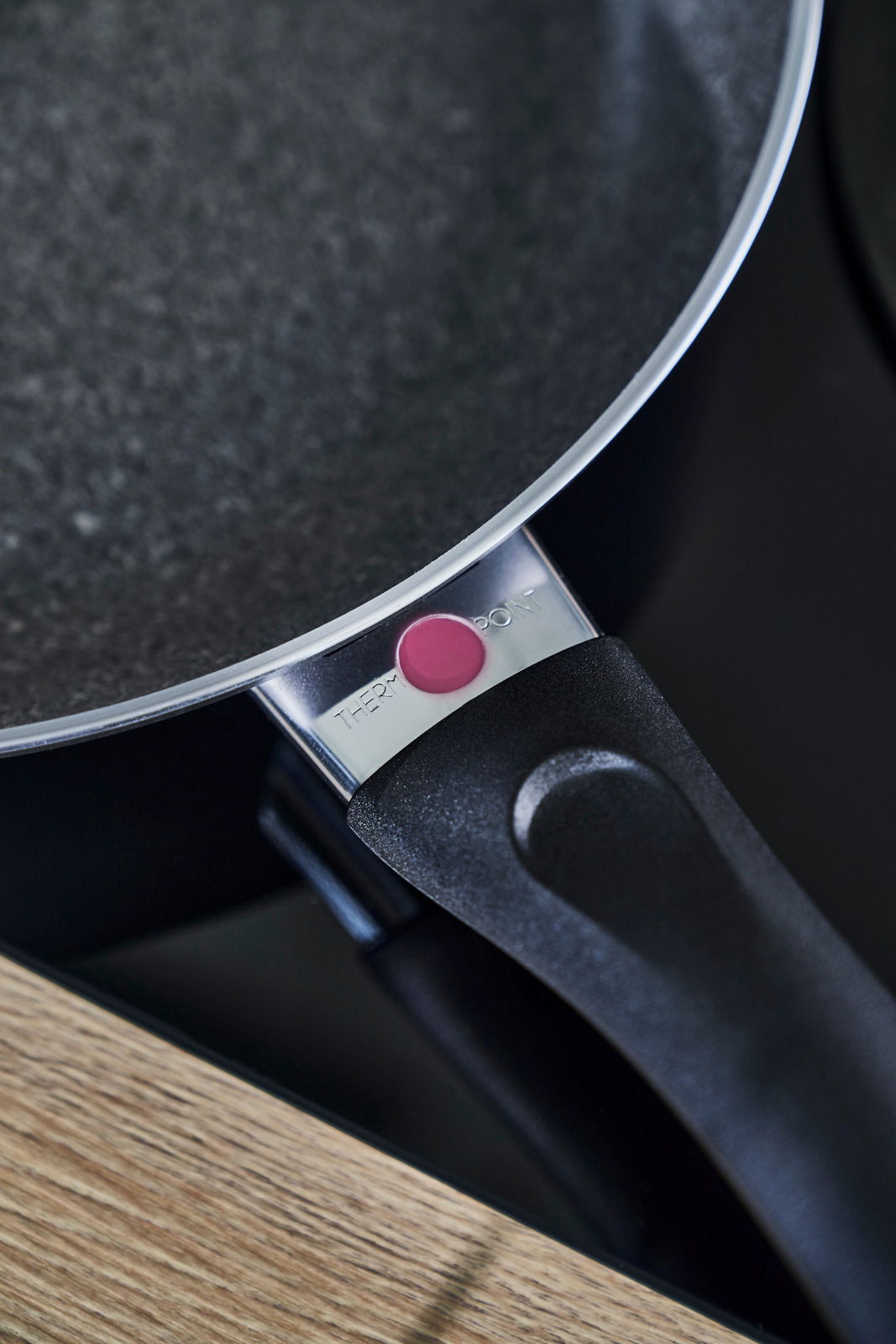 Nahaufnahme einer schwarzen Pfanne mit Thermopoint-Anzeige am Griff, auf einem Herd stehend.