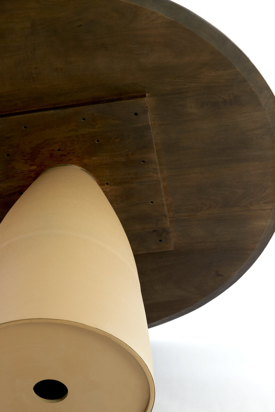 Unteransicht eines runden Esstisches mit konischem Sockel und dunkler Holzoberfläche.