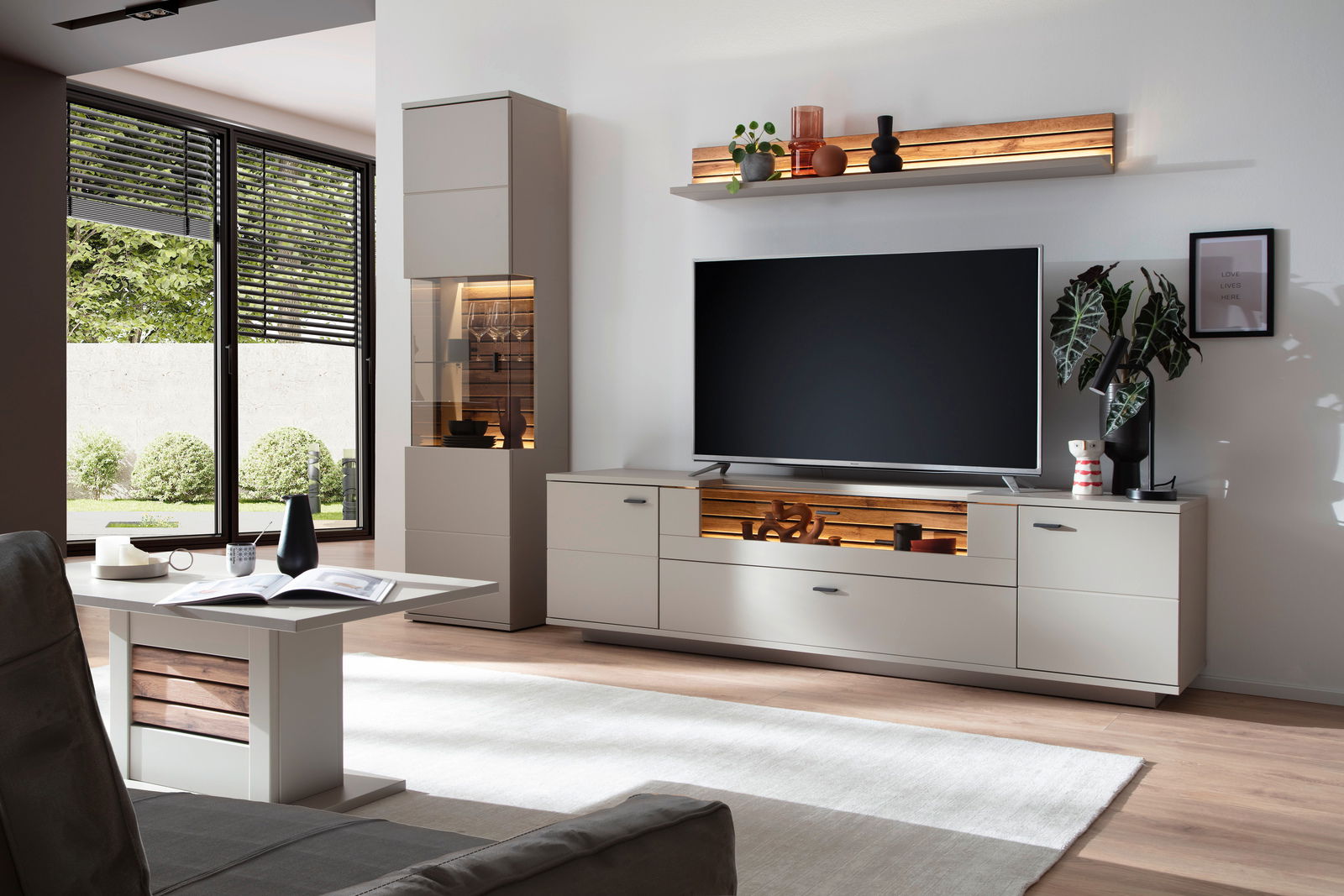 Zurbrüggen Wandkombination LÜTTICH Moderne Wandkombination in einem hellen Wohnzimmer mit TV-Schrank, Vitrine und dekorativen Regalen, seitliche Perspektive