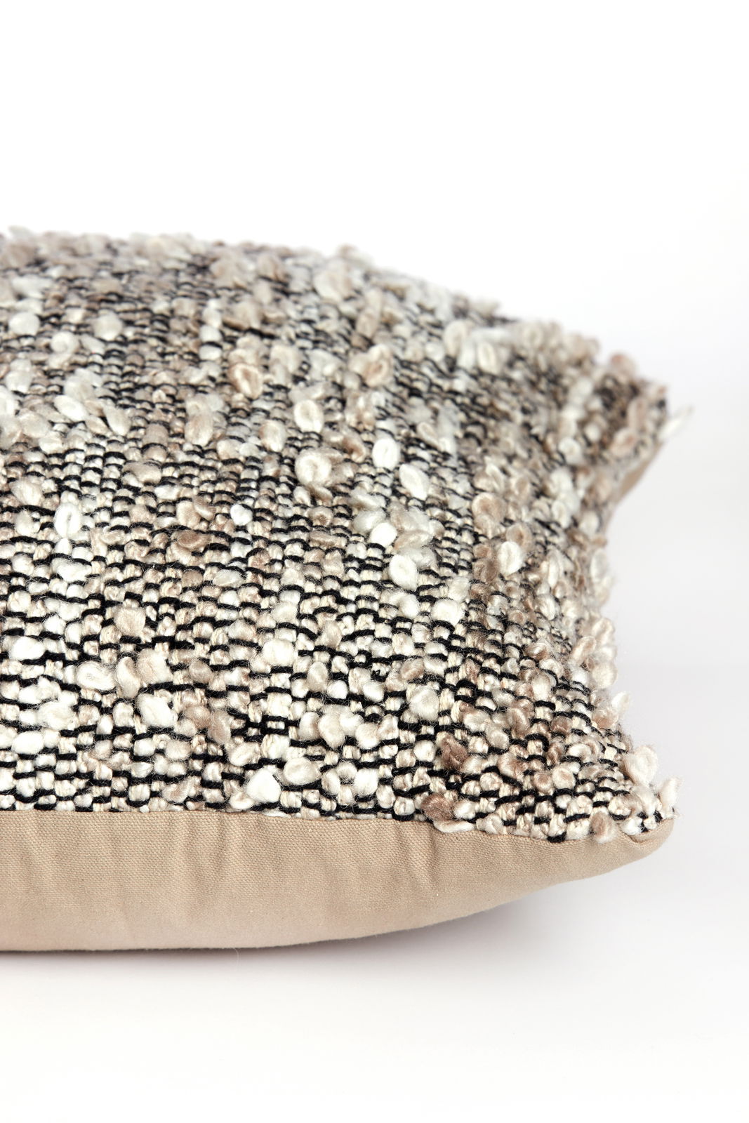 Nahaufnahme eines strukturierten Kissens mit gemustertem Stoff in neutralen Tönen, seitliche Perspektive