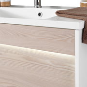 Nahaufnahme eines modernen Waschplatzes mit Holzoptik und integrierter Beleuchtung, seitliche Perspektive