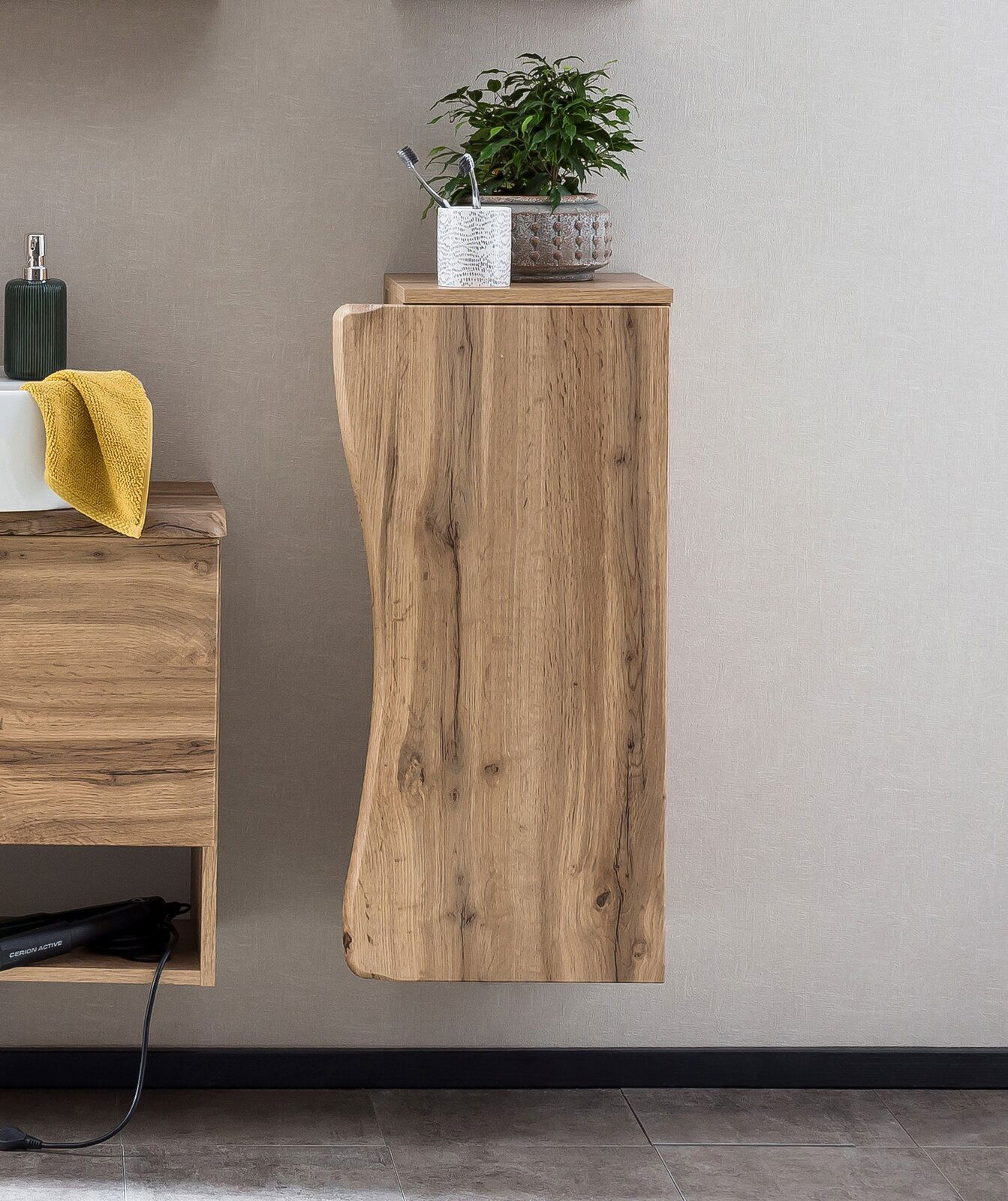 Moderner Unterschrank aus Holz mit natürlicher Maserung, seitliche Perspektive, dekoriert mit Pflanze und Zahnbürstenhalter auf der Oberseite.