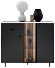Vooraanzicht van het Dieter Knoll-highboard RIANI in een donkere uitvoering, met decoratieve voorwerpen op het bovenblad en een verlicht glazen element.