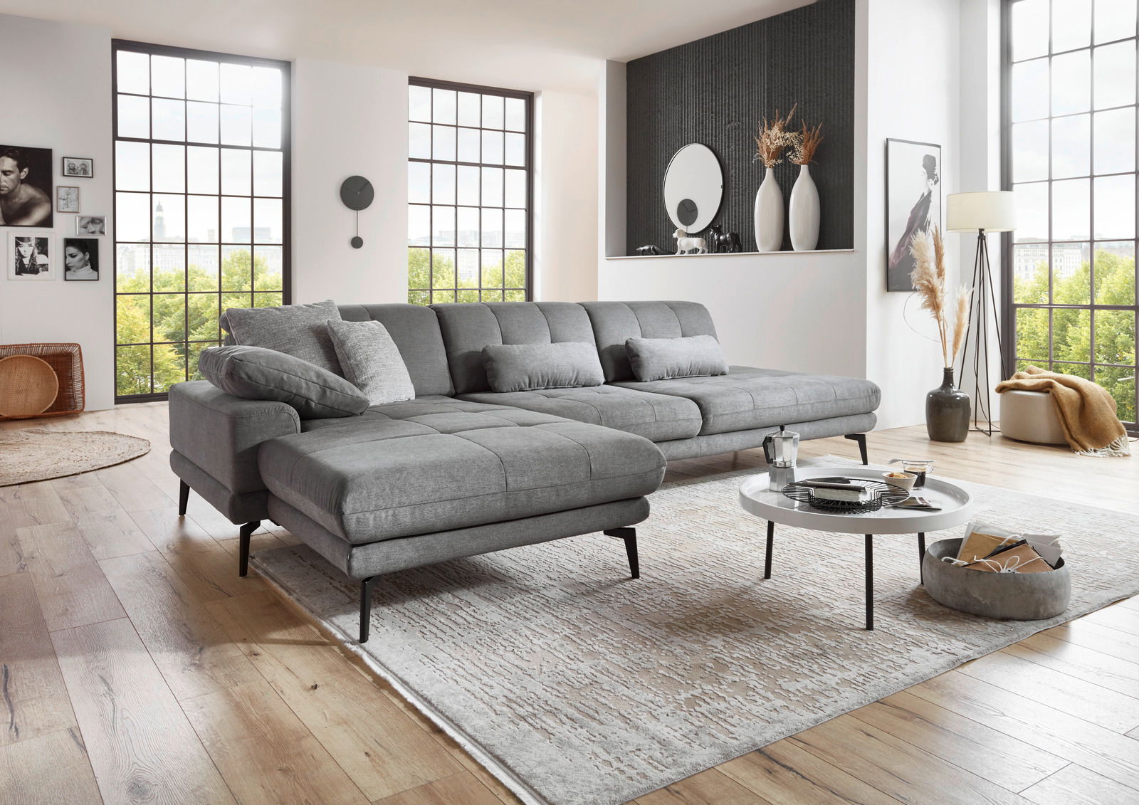 Graue Longchairkombination mit XXL-Hocker in modernem Wohnzimmer, seitliche Perspektive.