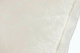 Nahaufnahme eines weißen, strukturierten Stoffes mit floralen Mustern und weichem Rand.