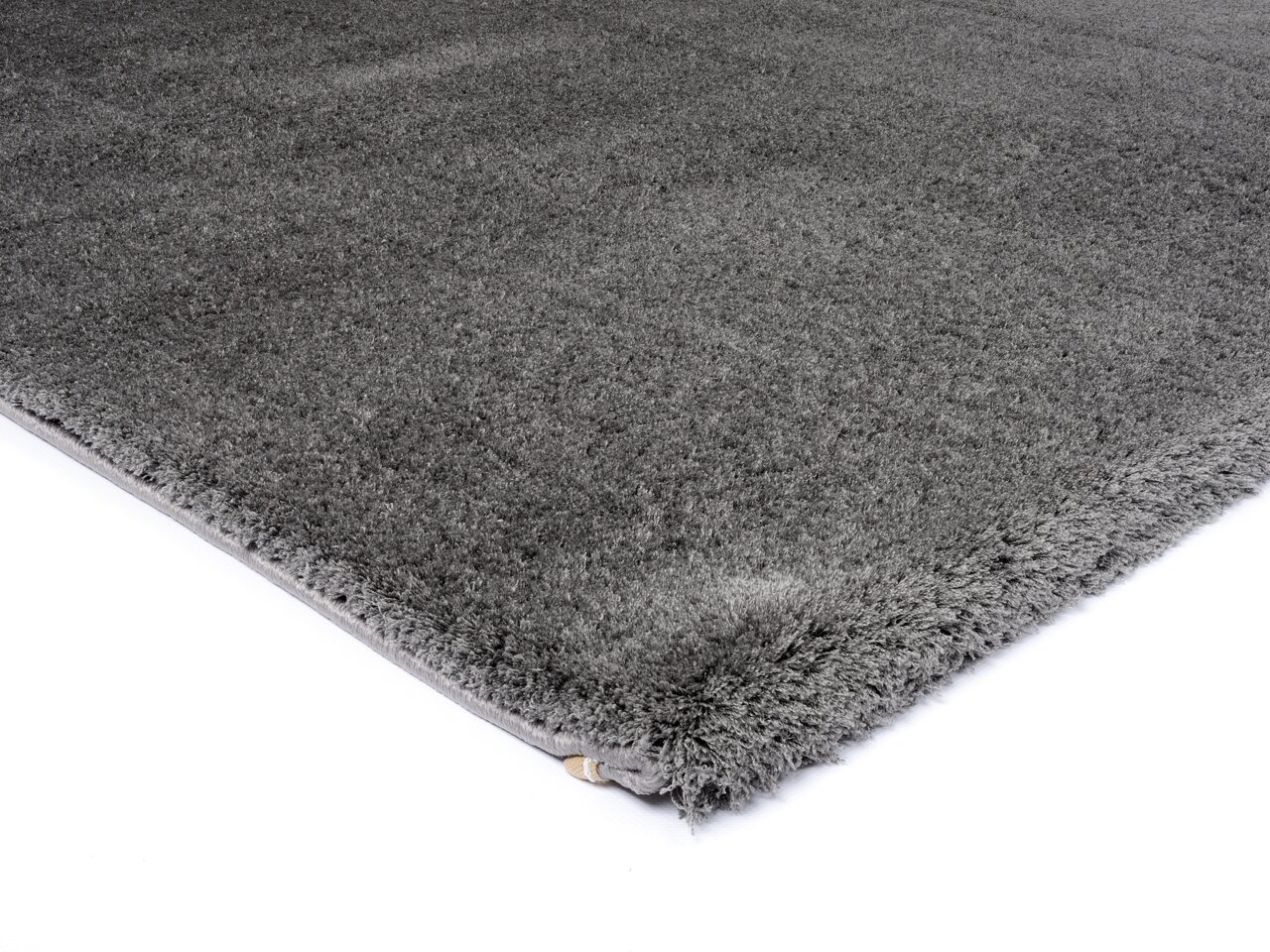 Grauer Hochflor-Teppich in Nahaufnahme, perspektivisch von der Seite fotografiert.