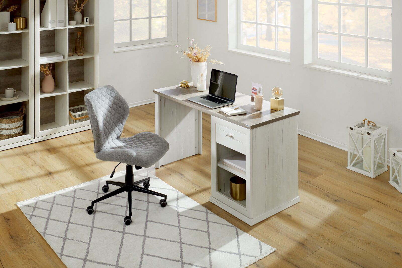 Moderner Schreibtisch in heller Holzoptik mit Laptop und Dekorationen, seitliche Perspektive.