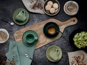 Draufsicht auf ein rustikales Kaffee-Arrangement mit grün gesprenkelten Tassen und Untertassen auf Holzbrett, Espresso, Löffeln, Gebäck und dekorativen Beeren auf dunklem Tisch