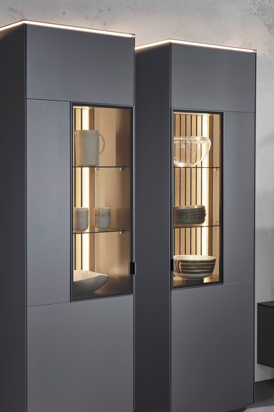 Moderne Vitrine mit Glasfronten, beleuchtetem Innenraum und stilvoller Präsentation von Geschirr, seitliche Perspektive