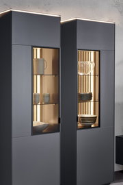 Moderne Vitrine mit Glasfronten, beleuchtetem Innenraum und stilvoller Präsentation von Geschirr, seitliche Perspektive