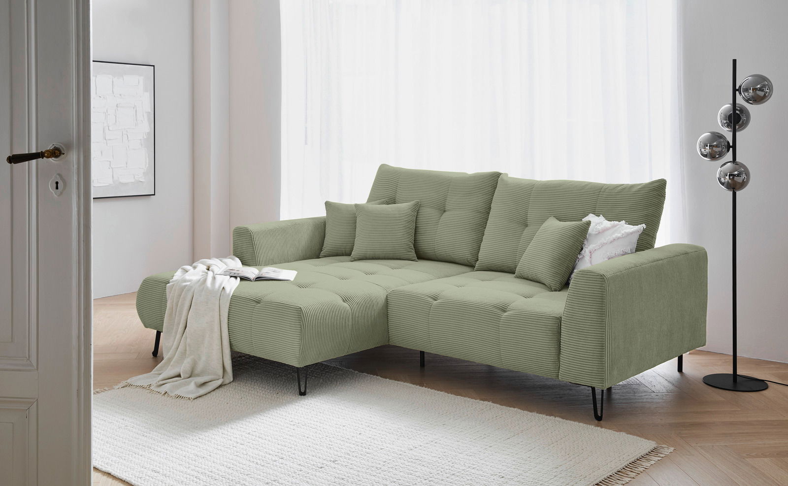 Grüne Ecksofa mit Ottomane in einem modernen Wohnzimmer, seitliche Perspektive