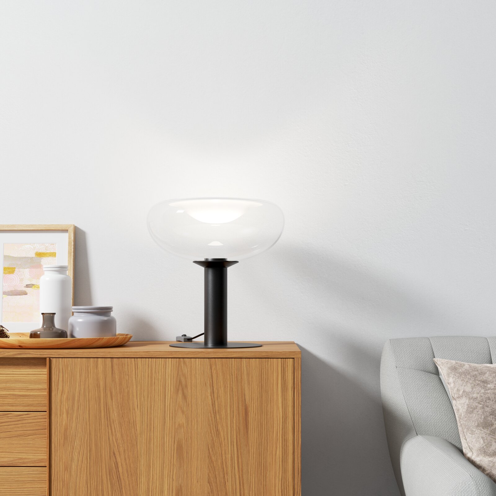 Dieter Knoll Tafellamp TISCHLEUCHTE Moderne Tischleuchte mit klarem Glas und schwarzem Sockel auf einem Holzschrank, seitliche Perspektive.