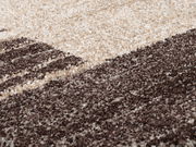 Nahaufnahme eines flauschigen Teppichs in Creme- und Brauntönen, perspektivisch von der Seite aufgenommen.