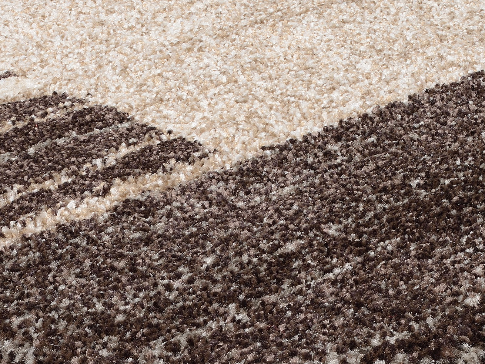 Nahaufnahme eines flauschigen Teppichs in Creme- und Brauntönen, perspektivisch von der Seite aufgenommen.