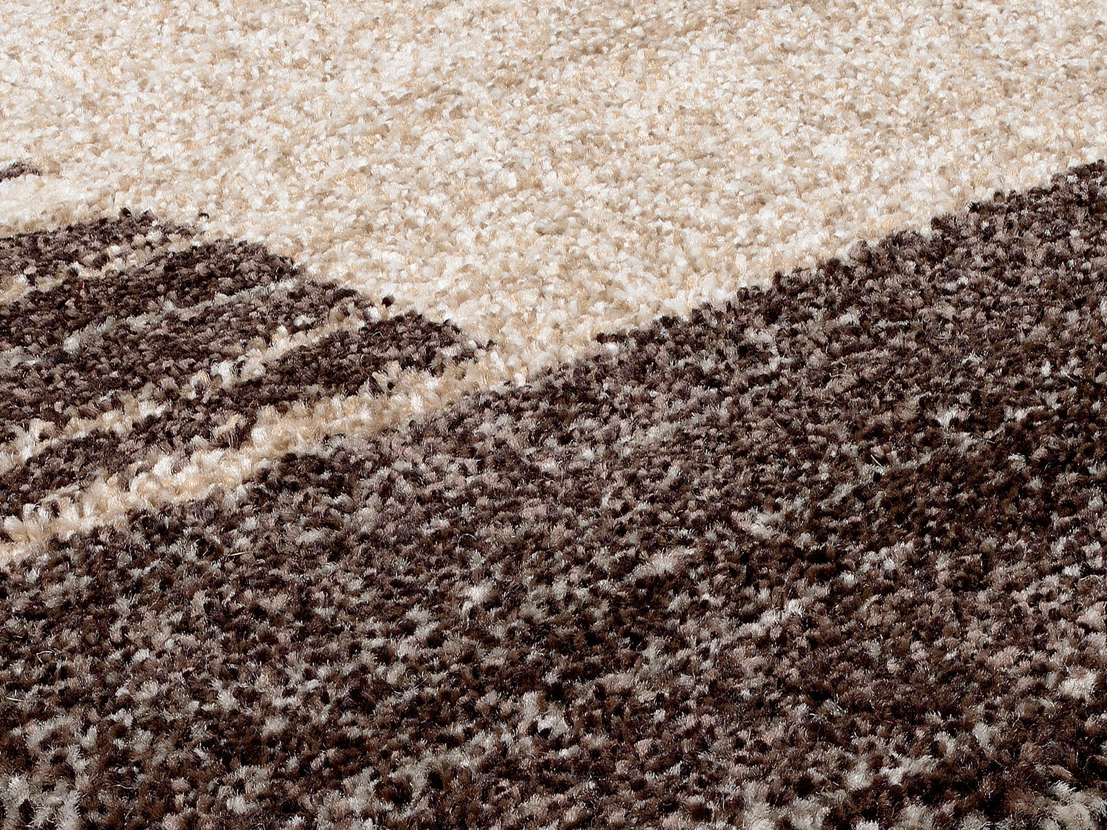 Nahaufnahme eines flauschigen Teppichs in Creme- und Brauntönen, perspektivisch von der Seite aufgenommen.