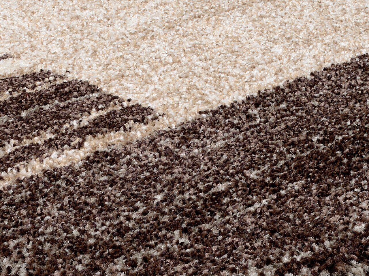 Nahaufnahme eines flauschigen Teppichs in Creme- und Brauntönen, perspektivisch von der Seite aufgenommen.