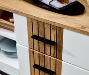 Nahaufnahme eines modernen Schuhschranks mit Holz- und Weißelementen, schwarzen Griffen und dekorativen Gegenständen auf der Oberseite, aus seitlicher Perspektive.