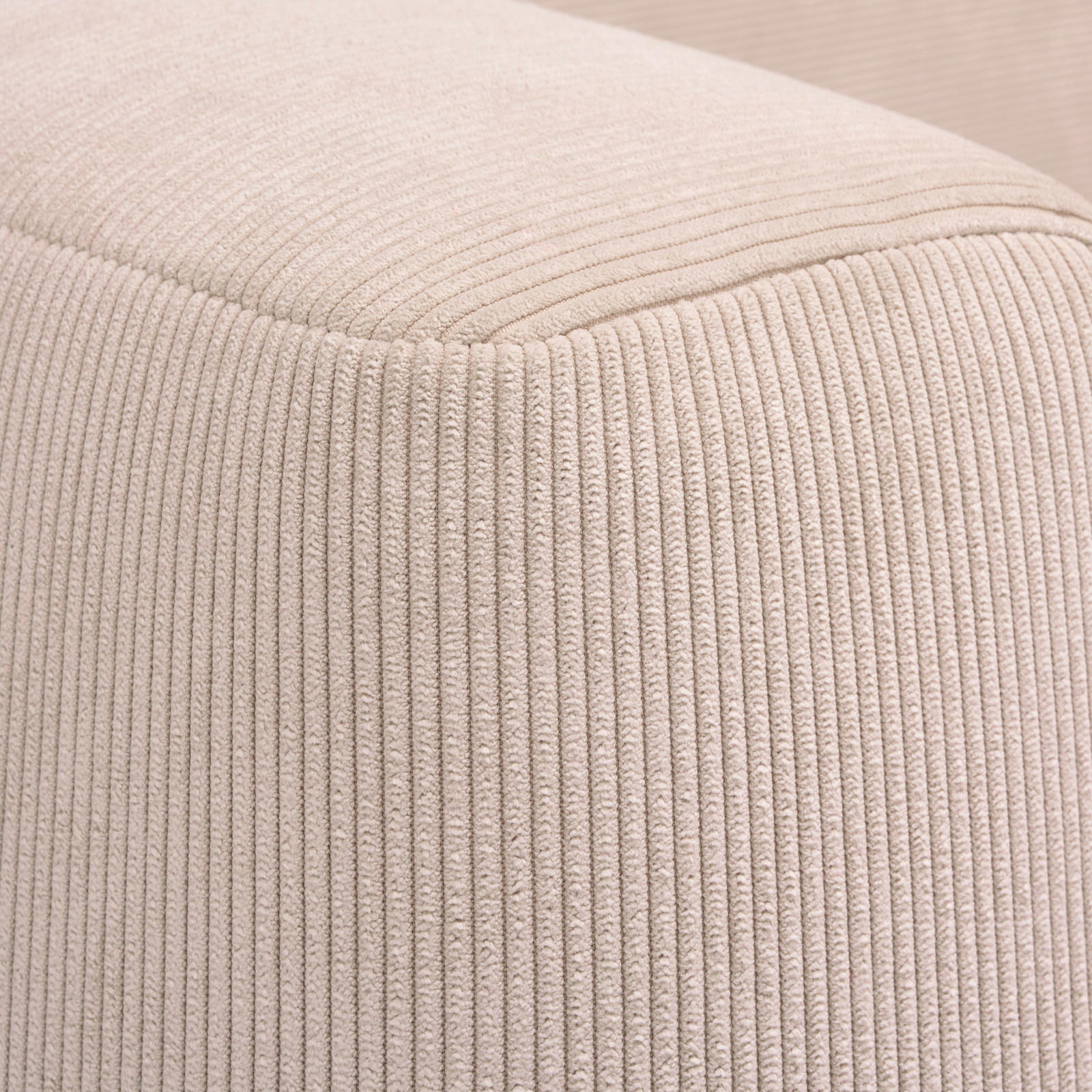 Nahaufnahme eines beigen, gerippten Stoffes eines Funktionssofas, perspektivisch von der Ecke aufgenommen.