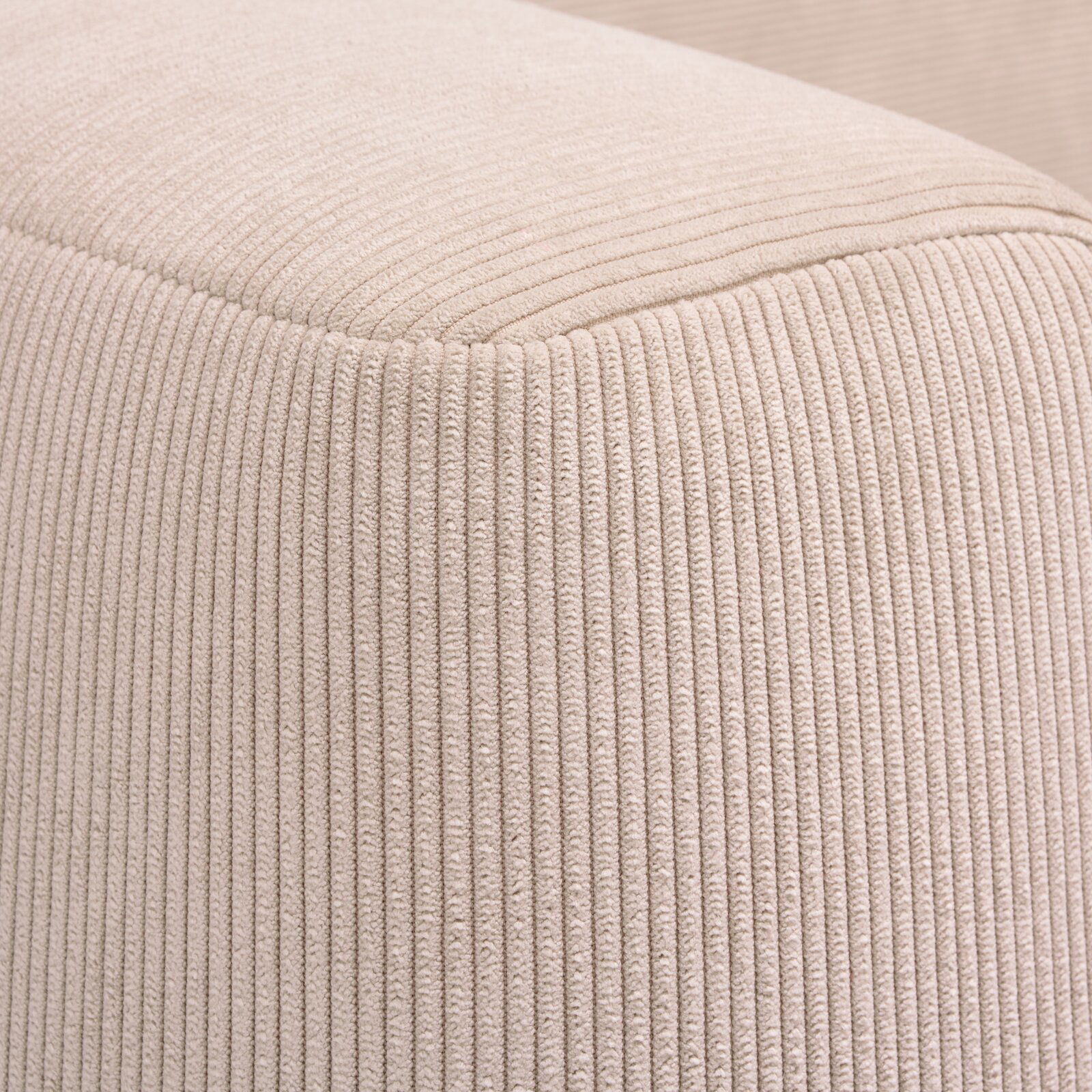 Nahaufnahme eines beigen, gerippten Stoffes eines Funktionssofas, perspektivisch von der Ecke aufgenommen.