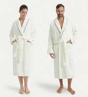 Zwei Personen tragen einen weißen Bademantel mit Schalkragen und schwarzer Paspelierung, frontal fotografiert.